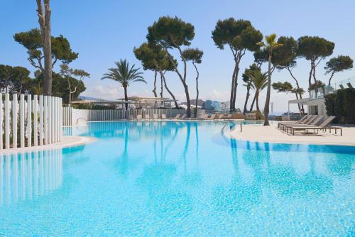 a swimming pool with blue water and palm trees at Meliá Calviá Beach in Magaluf