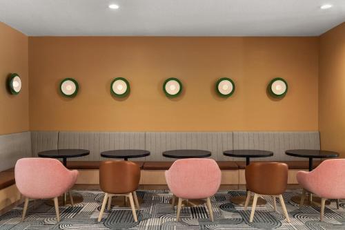 a waiting room with tables and chairs and clocks on the wall at EVEN Hotel Orlando International Airport by IHG in Orlando