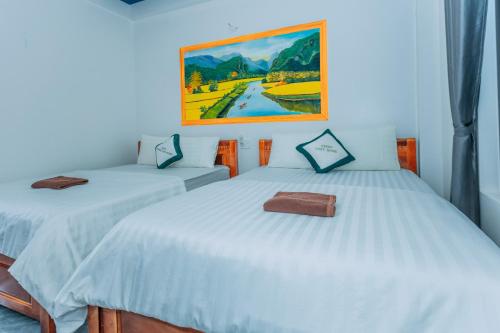 two beds in a room with a painting on the wall at Green Riverside Cosy Home in Bố Trạch