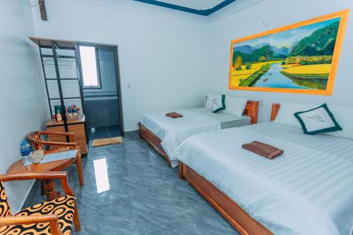a room with two beds and a painting on the wall at Green Riverside Cosy Home in Bố Trạch