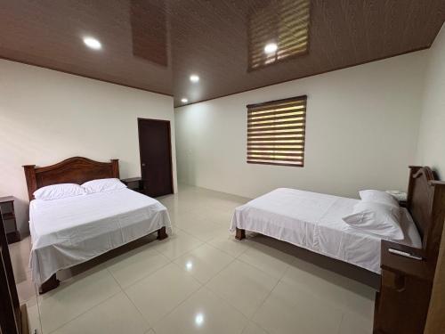 a bedroom with two beds and a window at Chato Arenal Lodge in Fortuna