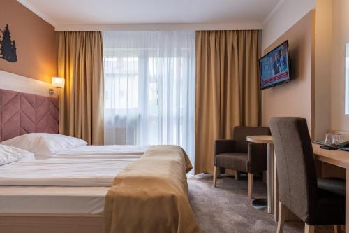 a hotel room with a bed and a desk at Pensjonat Carmen in Szklarska Poręba