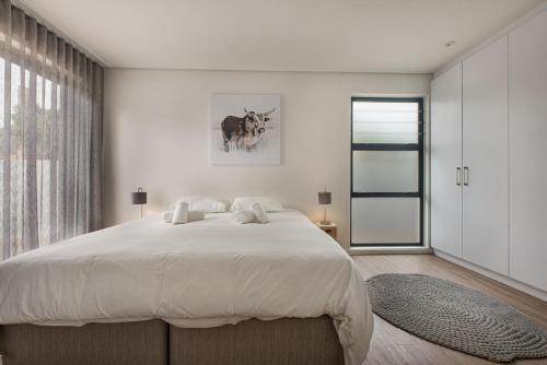 a white bedroom with a large bed and a window at 48 On Possession Island in Swakopmund