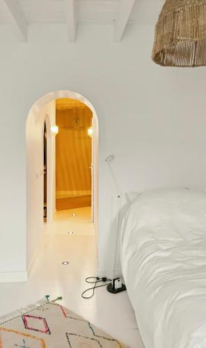 - une chambre avec un lit et un couloir avec une arche dans l'établissement Maison du couvent, à Arles
