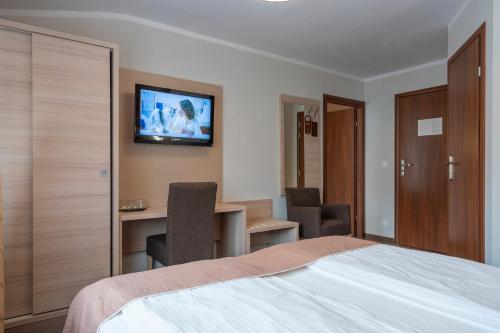 a bedroom with a bed and a desk and a television at Pensjonat Carmen in Szklarska Poręba