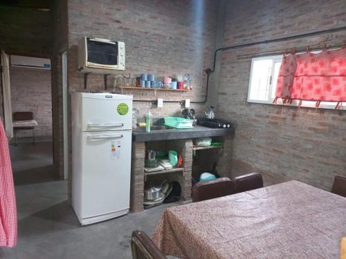 a kitchen with a white refrigerator and a table at Cabaña LA BALSA in Villa Urquiza
