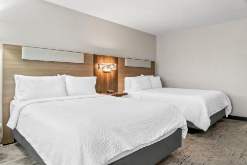 two beds in a hotel room with white sheets at Holiday Inn Express Lapeer by IHG in Lapeer