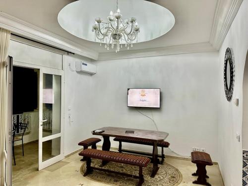 a table and benches in a room with a chandelier at 2-bedroom apartment in Yasmine Hammamet in Yasmine