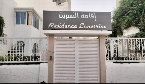 a white building with a sign and a garage at 2-bedroom apartment in Yasmine Hammamet in Yasmine