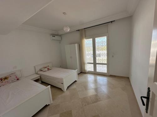 a white room with two beds and a window at 2-bedroom apartment in Yasmine Hammamet in Yasmine