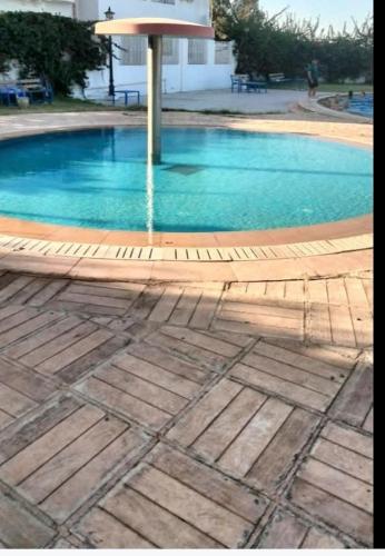 a large swimming pool with a umbrella and blue water at 2-bedroom apartment in Yasmine Hammamet in Yasmine