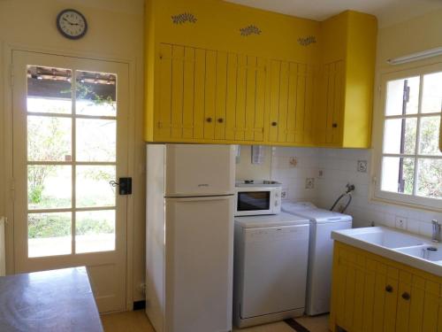 La cuisine est équipée de placards jaunes et d'un réfrigérateur blanc. dans l'établissement La Sauvagine, à Barjols