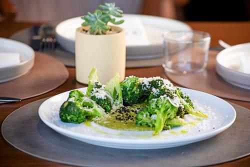 a white plate of broccoli on a table at voco Guadalajara Neruda by IHG in Guadalajara