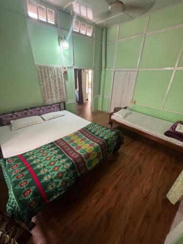 a bed in a room with green walls and wooden floors at Hemalata Heritage Home in Guwahati