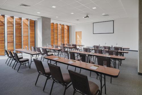 a classroom with tables and chairs and a projection screen at voco Guadalajara Neruda by IHG in Guadalajara