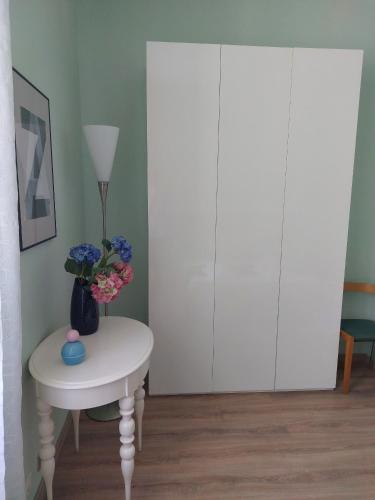 a white table with a vase of flowers on it next to a cabinet at A 50 passi dal lago - Affitti Brevi Italia in Capodimonte