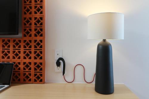 a black lamp sitting on a desk next to a wall at voco Guadalajara Neruda by IHG in Guadalajara