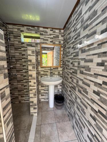 a bathroom with a sink and a brick wall at Mitiana Lodge Huahine in HUH