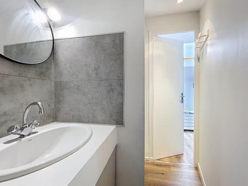 une salle de bain blanche avec un lavabo et un miroir dans l'établissement La Capsule, à Rouen