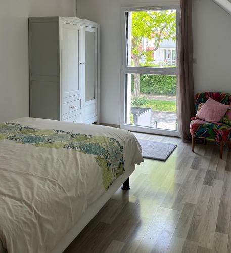 une chambre avec un lit et une grande fenêtre dans l'établissement Appartement duplex proche Strasbourg, à Lampertheim
