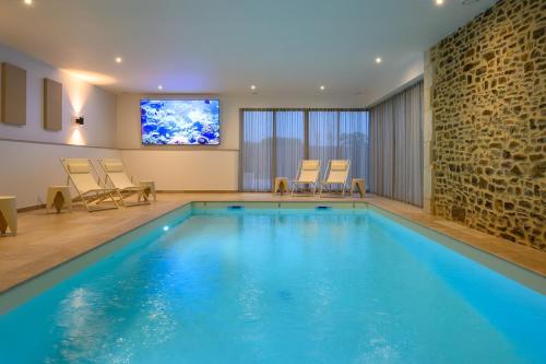 une piscine avec des chaises et une télévision dans une chambre dans l'établissement Domaine Saint Georges, à Saint-Sauveur-le-Vicomte