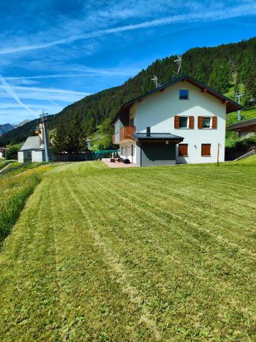 a large grass field in front of a house at appartamento PANORAMA in Pozza di Fassa
