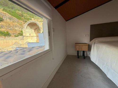 a bedroom with a window and a bed and a table at Alojamiento Jacuzzi Las Ruinas in Cazorla