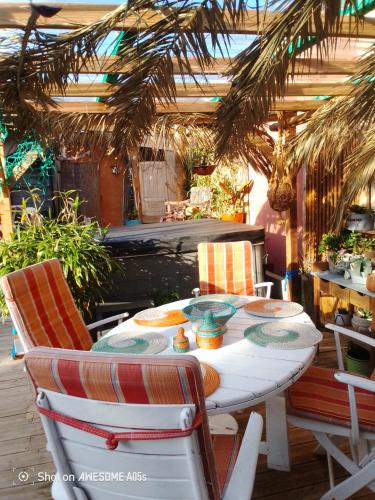 une table blanche et des chaises sur une terrasse dans l'établissement D'Ici ou D'ailleurs, à Barneville-Carteret