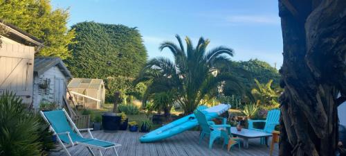 un toboggan bleu sur un patio avec des chaises et une table dans l'établissement D'Ici ou D'ailleurs, à Barneville-Carteret