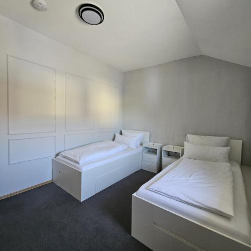 two beds in a room with white walls at Haus Ela in Sächsenheim