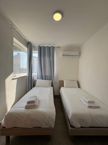 two beds in a small room with a window at Spacious Stay new 2 Bed and Balcony in Taʼ Penza