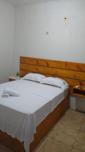 a bedroom with a large white bed with a wooden headboard at Casa Aconchego Flecheiras in Trairi