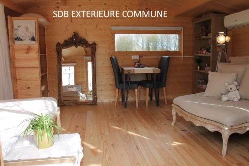 a living room with a table and a mirror at Chambre studio photo chalet SDB partagée à proximité in Chavagne