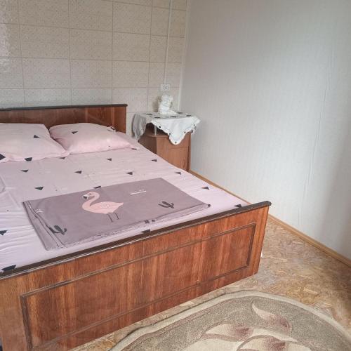 a bed with a wooden frame with a pink bird on it at Ципель 1 in Szack