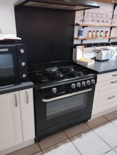 Il comprend une cuisine équipée d'une cuisinière noire et d'un four micro-ondes. dans l'établissement Grande maison BREST, à Brest