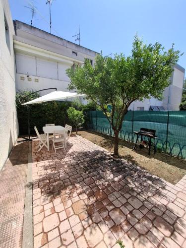 a patio with a tree and a table and chairs at La casa del delfino in Policoro
