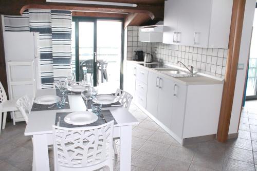 a kitchen with white cabinets and a table and chairs at Villa Anita Apartments in Capo dʼOrlando