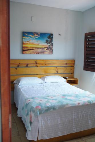a bedroom with a large bed with a wooden headboard at Casa Aconchego Flecheiras in Trairi