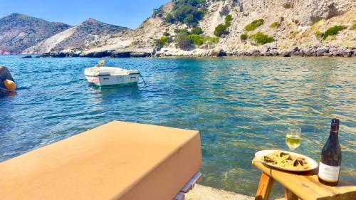 a bottle of wine and a plate of food and a boat in the water at Milos Boathouse-Between2seas Boutique in Areti