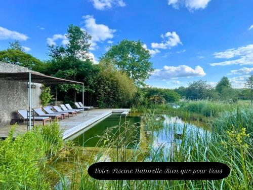 une terrasse avec des chaises longues à côté d'un étang dans l'établissement Domaine de la Beurrerie, 25