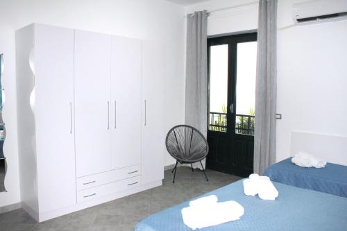 a bedroom with two beds and a chair and a window at Villa Anita Apartments in Capo dʼOrlando