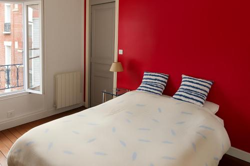 - une chambre rouge avec un lit doté d'oreillers bleus et blancs dans l'établissement Sunny Serenity: 2-room Charm in Boulogne, à Boulogne-Billancourt