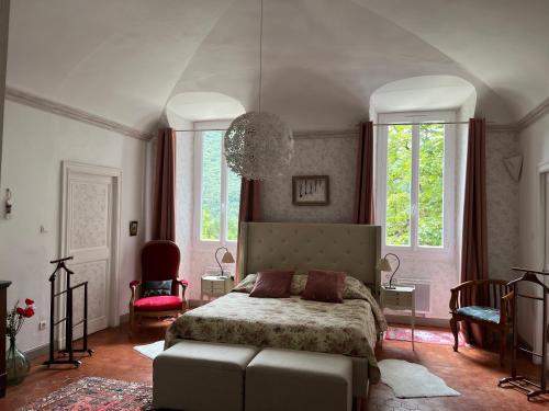 a bedroom with a bed and a couch and windows at Les Dames de Saint Florent in Saint-Florent-sur-Auzonnet