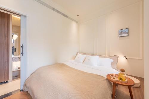 a white bedroom with a bed and a table at TUIWA Garden Holiday Villa in Qingdao