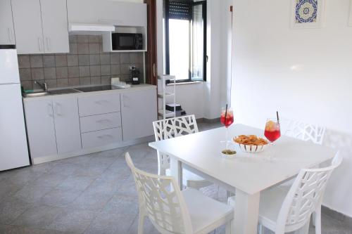 a white kitchen with a white table and chairs at Villa Anita Apartments in Capo dʼOrlando