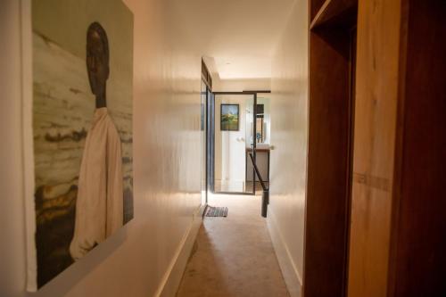a hallway with a white wall and a hallway with a mirror at Green Valley Residence By Serenova Retreats in Kigali