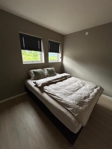 a bed in a bedroom with two windows at Apartment Suite in Os in Osøyro