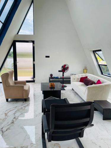 a living room with a white couch and chairs at The A-Frame house in Kūvattūr