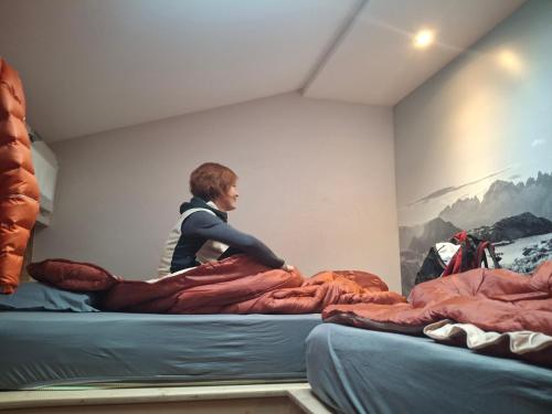 a man is sitting on top of a bed at Inner Holiday Dolomites 5 in Dimaro
