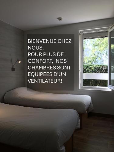 two beds in a room with a sign on the wall at Fast Hotel Colmar Houssen in Houssen